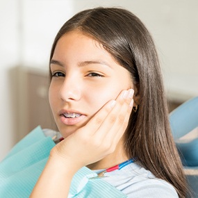 Teen with something stuck in braces holding cheek