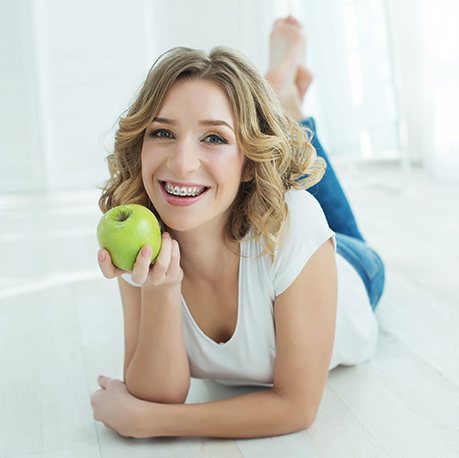 Young woman with braces eating an apple