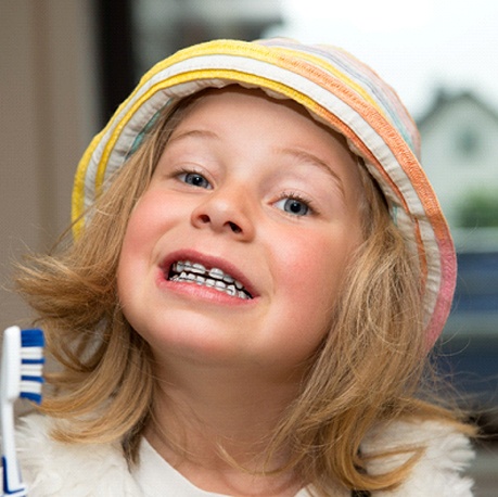 A young child brushing their teeth while wearing braces in Cumming