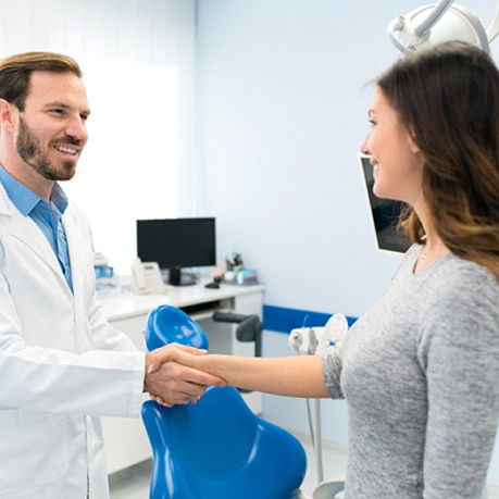 Dentist shaking hands with young woman patient