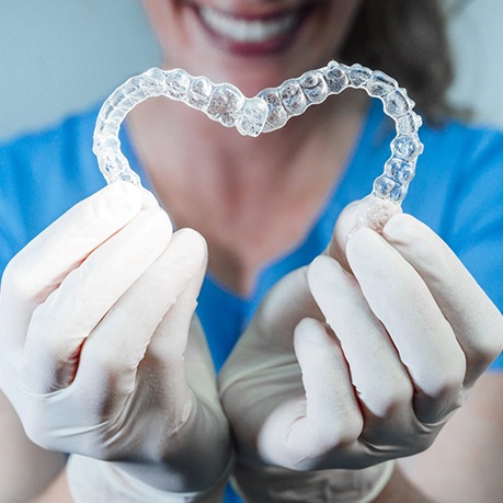  Dentist making heart shape with Invisalign aligners