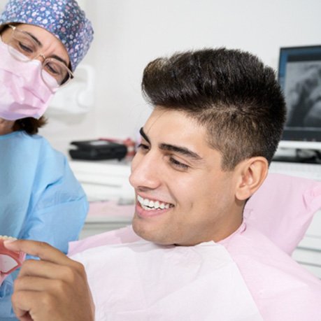 Orthodontist showing smiling patient clear aligner in office
