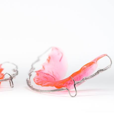 An image of two retainers laying on a surface, complete with pink plastic coloring