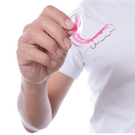 A person holding a retainer in their hand in preparation for inserting it into their mouth