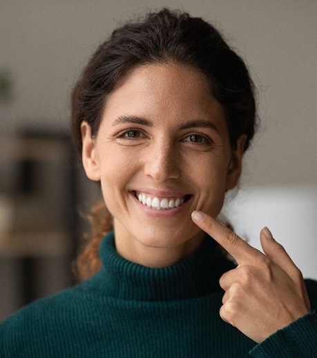 Happy woman pointing at her straight teeth