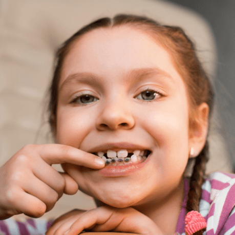 Young girl pointing to her orthodontic system