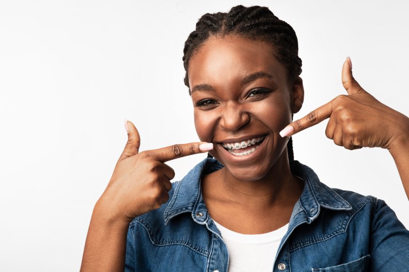 an adult woman pointing to her metal braces