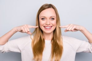 woman smiling and pointing at teeth