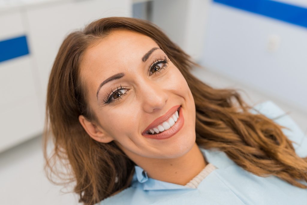 Woman with straight teeth smiling in orthodontist's treatment chair