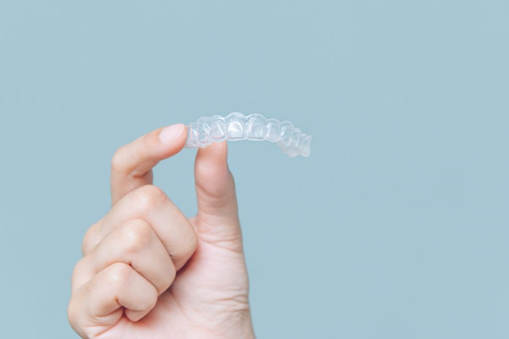 Patient holding up Invisalign clear aligner