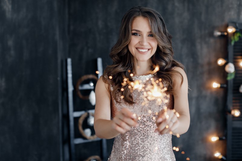 Smiling woman holding sparklers for New Year’s