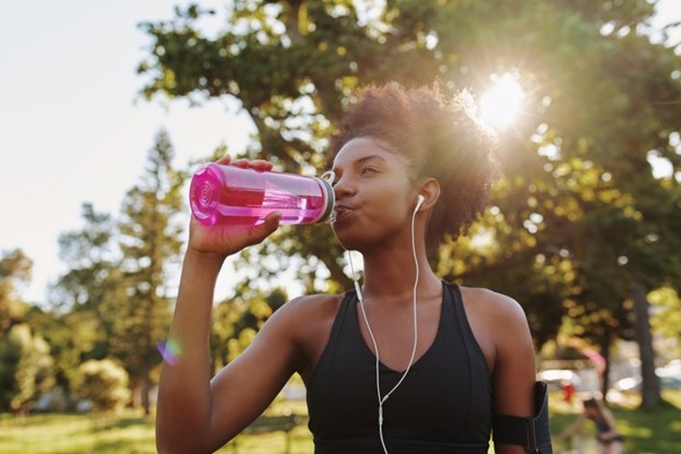 Woman drinking from her water bottle during the summer.