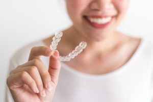 smiling person holding Invisalign aligner