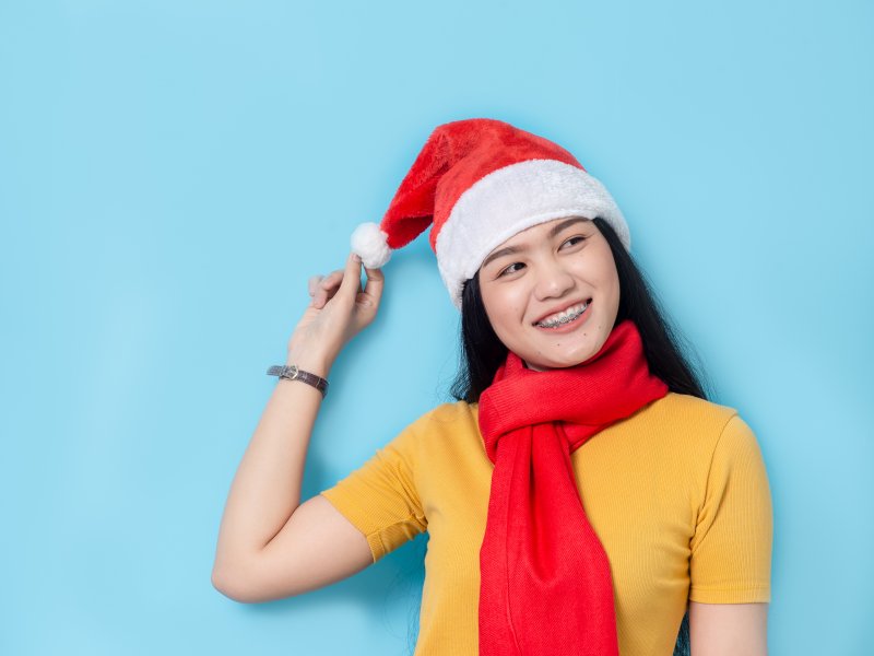 woman with braces smiling in a Santa hat