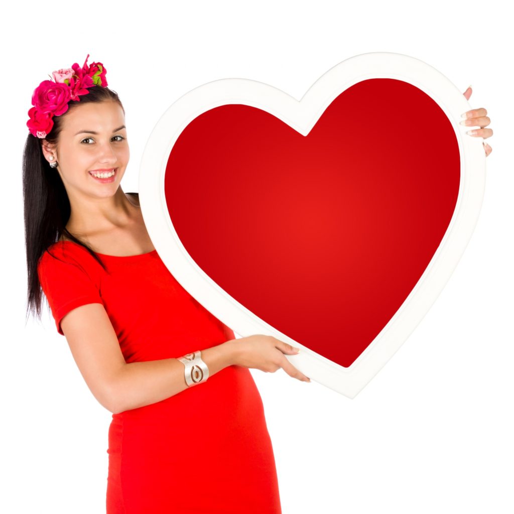 person smiling and holding up large paper heart