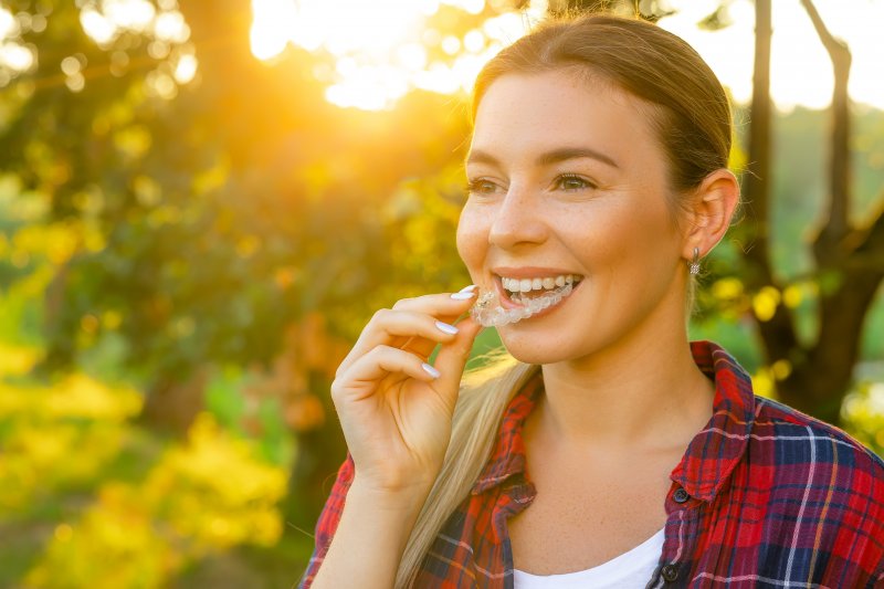 A woman placing her Invisalign tray while walking in summer weather