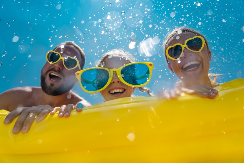 Smiling family wears sunglasses on raft.