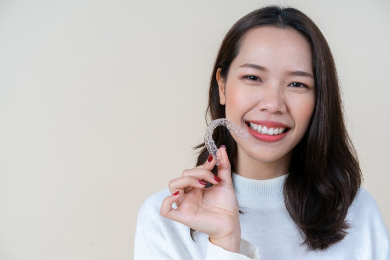 person smiling and holding Invisalign