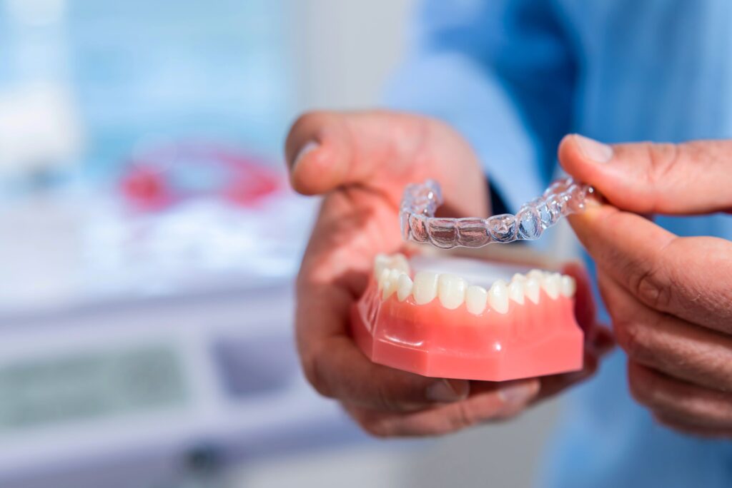 Dentist pulling clear aligner off sample teeth