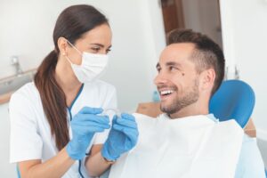 Doctor holding clear aligner while working with patient. 