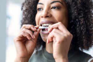 Woman with curly hair inserting Invisalign over upper arch
